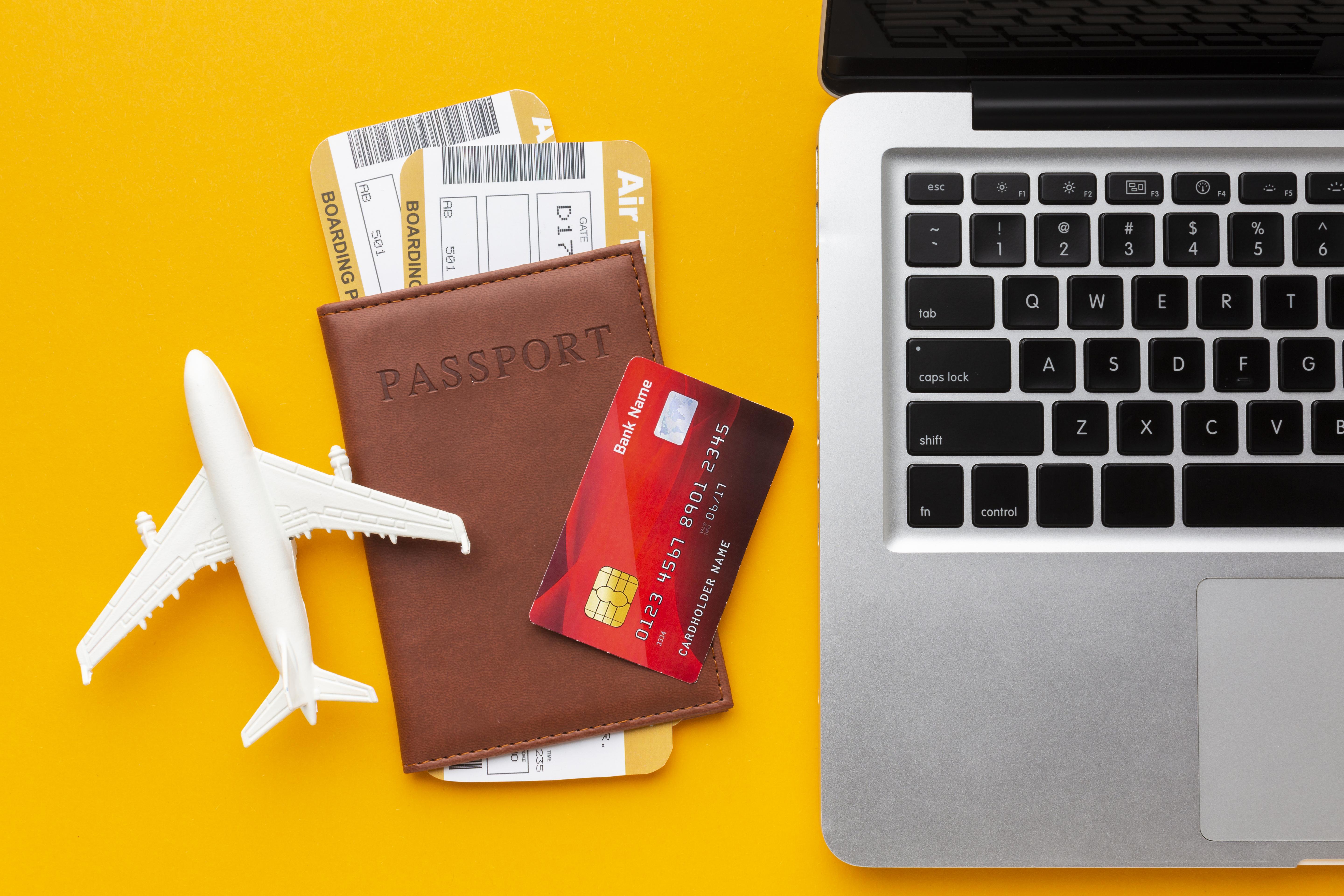 Passport, travel documents, and laptop on desk